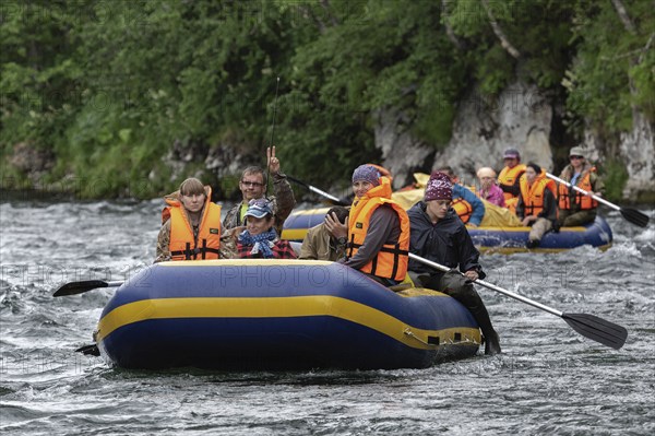 FAST RIVER, KAMCHATKA PENINSULA, RUSSIAN FAR EAST, JULY 15, 2016: Summer rafting on Kamchatka in gloomy cloudy weather: rafting boat with tourists on board floats on waves on mountain river