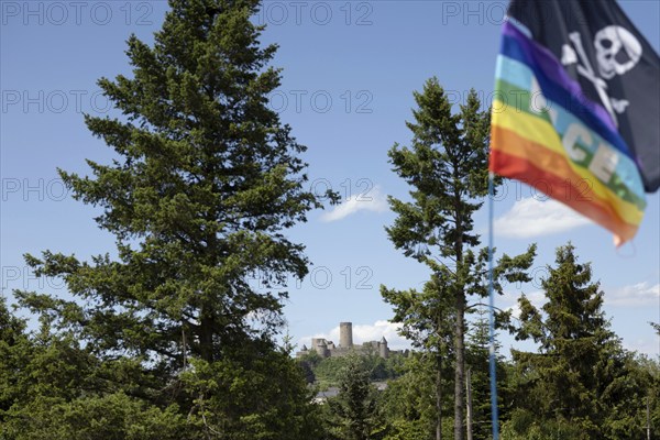 Adenau, Germany, 8 June 2024: The Nürburg can be seen in the background while a rainbow flag and a pirate flag fly on a tent at one of the Rock am Ring campsites. The festival takes place at the Nürburgring race track near the town of Adenau from 7 to 9 June 2024, Europe