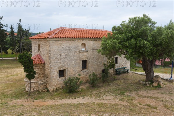 A historic stone building in a rural setting with a large tree, Metochi of the Monastery of St Paul, Néa Fókea, Nea Fokea, Kassandra Peninsula, Halkidiki, Halkidiki, Greece, Europe