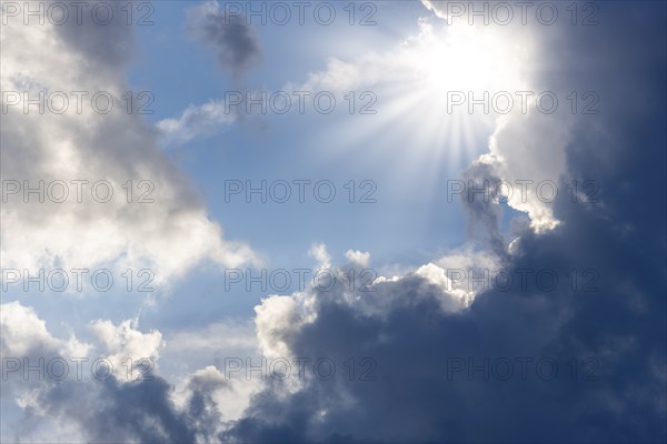 Rain clouds with sun shining through, rays of sunshine, blue sky