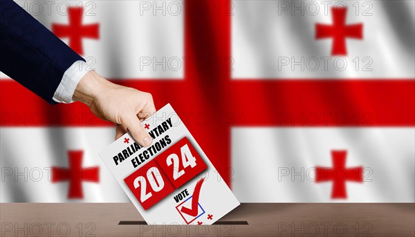 Georgian parliamentary elections. Hand holding ballot in voting ballot box with Georgian flag in background