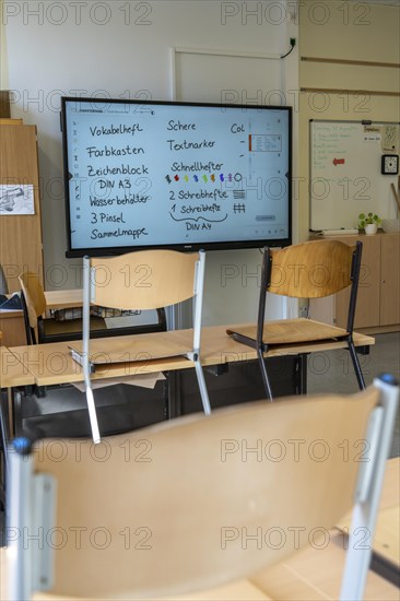 Classroom of a fourth grade, after school, the building is older but in good condition, modern teaching materials, interactive, digital whiteboard