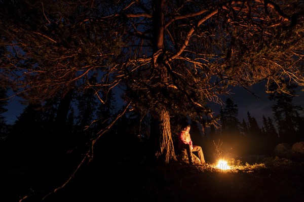 Man in the evening at a bivouac with campfire, Lapland, Sweden, Scandinavia, Europe