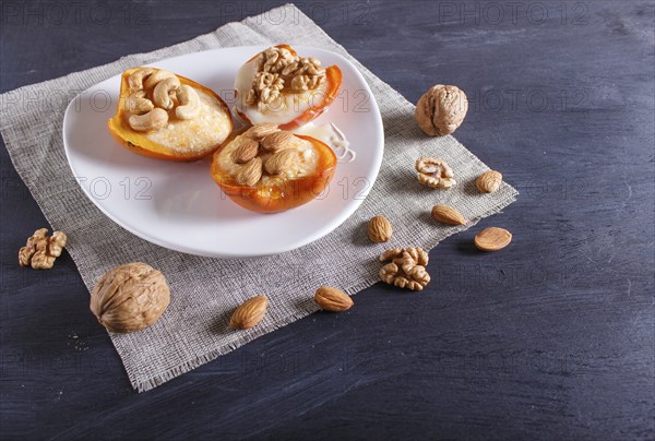 Persimmon dessert with curd, nuts and milk cream on black wooden background. close up, copy space