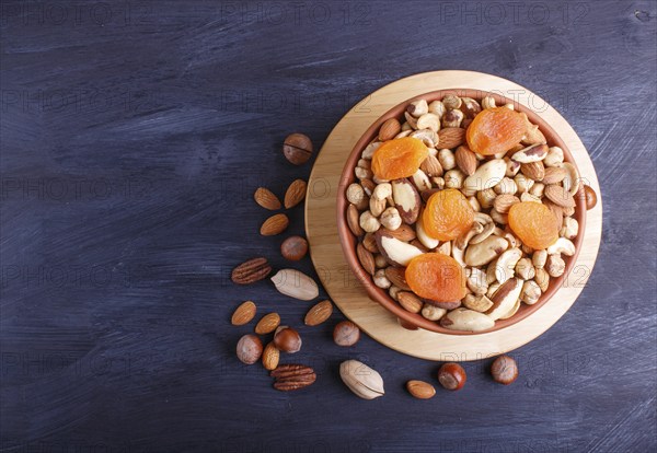 Mixed different kinds of nuts in ceramic bowl on black wooden background with copy space. hazelnut, brazil nut, almond, pumpkin seeds, cashew. top view