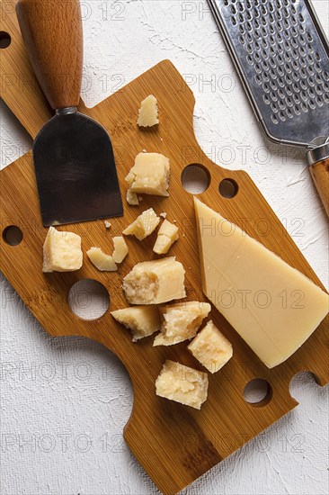 Hard cheese, parmesan, on a cutting board, cheese knife, grater, top view, no people