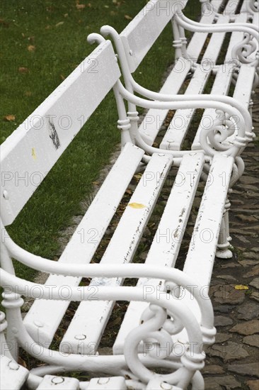 Old white painted wood and tubular steel sitting benches in a row, Prague Castle district, Prague, Czech Republic, Europe