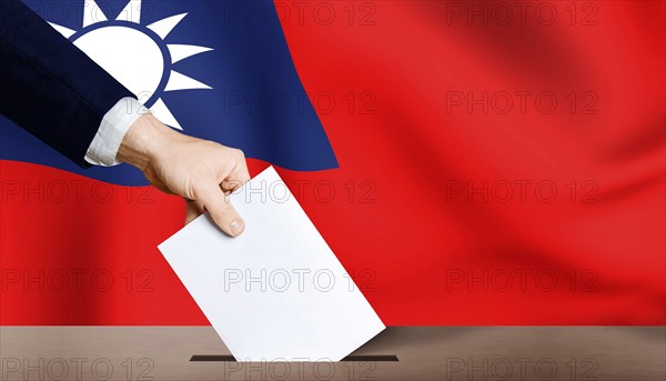 Hand holding ballot in ballot box with Taiwan flag in background. Taiwan presidential election