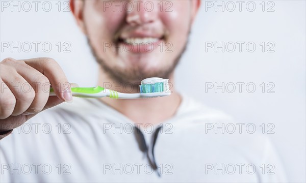 Hand of man showing toothbrush with toothpaste isolated. Close up of hands holding brush with toothpaste