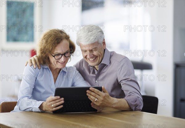 Symbolic photo. A woman and a man sit together at a table with a tablet and talk. Berlin, 13.08.2024