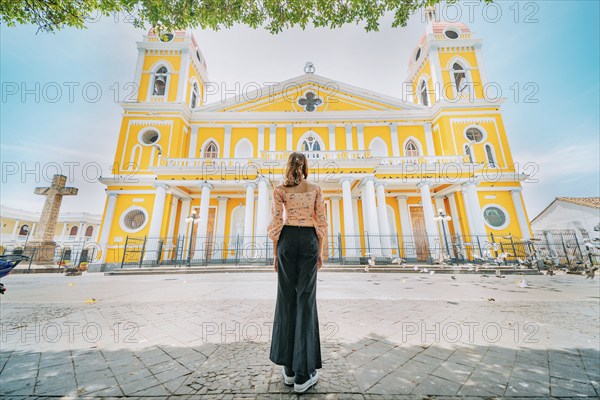 Rear view of a tourist woman in front of a cathedral in a tourist square. Back view of a beautiful tourist in the tourist plaza of Granada, Nicaragua, Central America