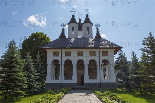 Exterior view of an Orthodox church with white walls and black domes under a clear blue sky, Cheia Romanian Orthodox Monastery, Maneciu, Maneciu, Prahova, Wallachia, Romania, Europe