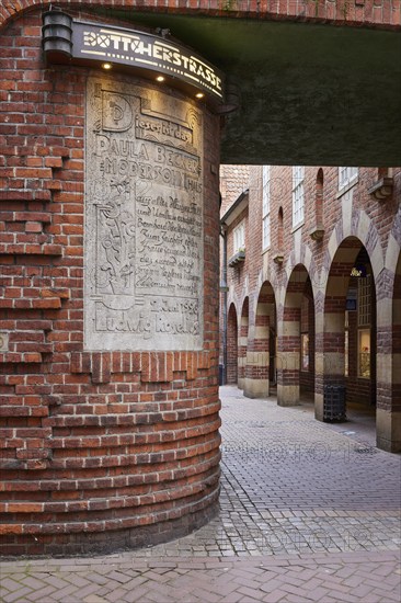 Illuminated sign Böttcherstrasse, sign embedded in the house wall to the artist Paula Modersohn-Becker and brick houses with arcades in the Böttcherstrasse in Bremen, Hanseatic city, state of Bremen, Germany, Europe