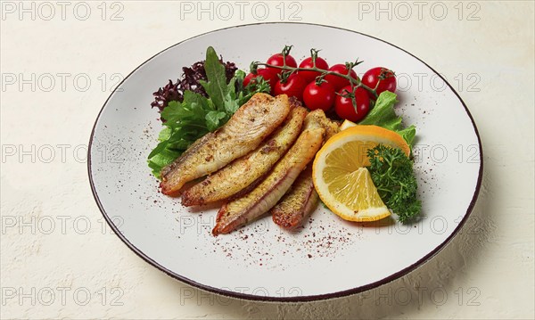 Fried Tilapia fish fillet, in spices, with cherry and salad, on a white plate, homemade, no people