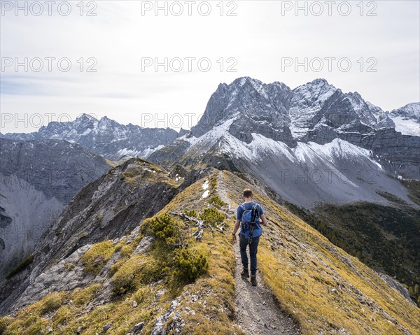 Mountaineer on a hiking trail on the ridge of Hahnkampl, mountain panorama with rocky steep peaks, view of summit Lamsenspitze, Karwendel Mountains, Alpenpark Karwendel, Tyrol, Austria, Europe