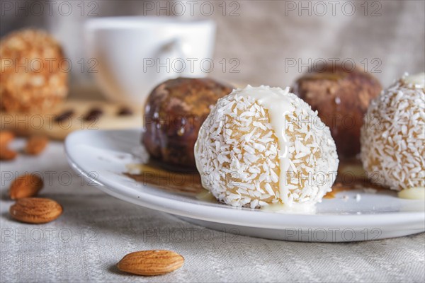 Energy balls cakes with chocolate caramel and coconut on white plate on linen napkin, selective focus, close up