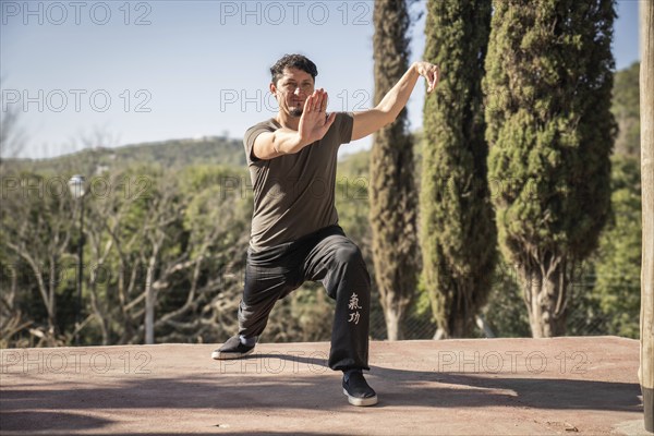 A man immerses himself in the practice of Kung Fu, a Chinese martial art, in the stance within the form of Xiao Ba Ji Quan in a natural setting. Connection between mind, body, and environment