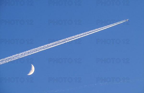 Aeroplane in the sky, vapour trail, crescent moon, waxing crescent moon, over Frankfurt am Main Germany