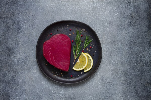 Fresh red tuna fillet, for steak, raw, top view, on a black plate, no people