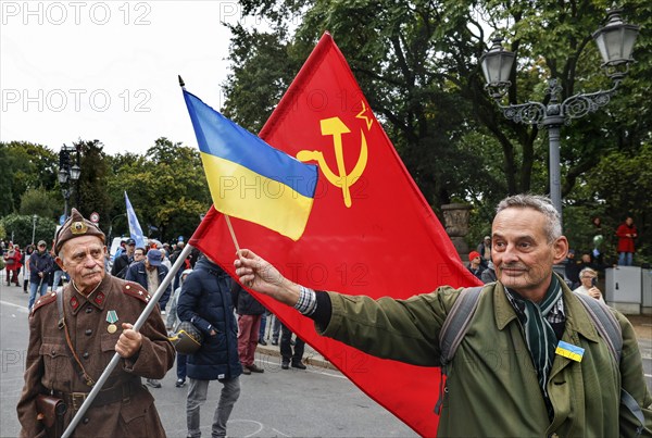 A Ukrainian man holds a Ukrainian flag in front of the former flag of the Soviet Union held by a man in Russian uniform at the counter-demonstration Your peace is our death sentence, Berlin, 03/10/2024, Berlin, Berlin, Germany, Europe