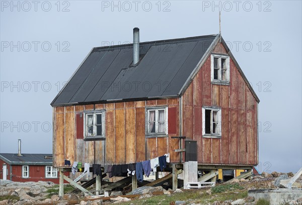 Small red house, clothesline with hanging laundry, remote Arctic Inuit settlement Ittoqqortoormiit, Scoresbysund or Scoresby Sund or Greenlandic Kangertittivaq, East Greenland, Greenland, North America