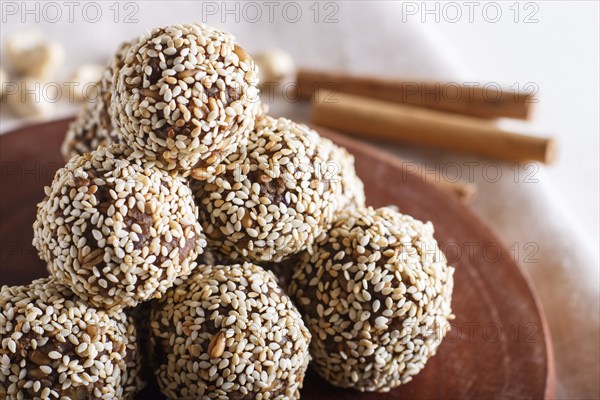 Energy balls cakes with almonds, sesame, cashew, walnuts, dates and germinated wheat on wooden board, side view, close up