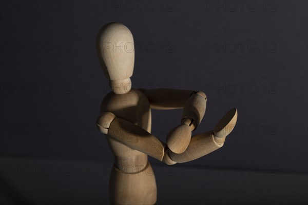 Wooden mannequin shows obscene gesture fuck off with hands on gray background. protest, riot, agression, contempt concept. copy space, hard light