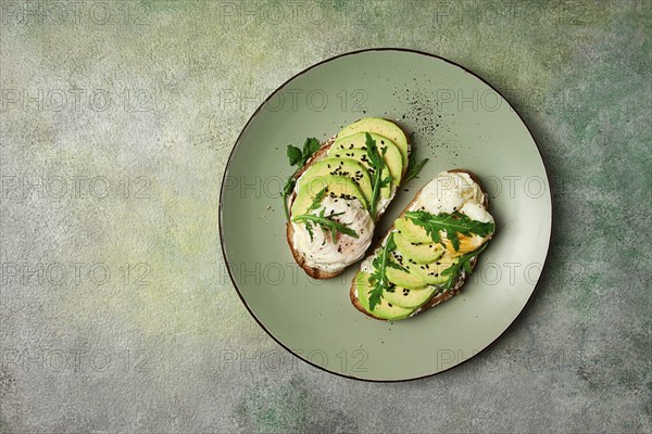 Sandwich with cream cheese, sliced avocado and boiled egg, arugula, on grainy bread, homemade, breakfast, no people