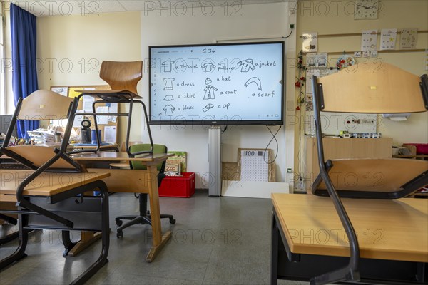 Classroom of a fourth grade, after school, the building is older but in good condition, modern teaching materials, interactive, digital whiteboard