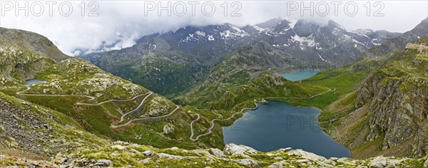 Panoramic view of left serpentines narrow bends from ascent pass road to alpine pass Colle del Col de Nivolet, right foreground mountain lake Lago Agnel, rear reservoir Lago Serru Serrù, Gran Paradiso National Park, Ceresole Reale, Piedmont, Italy, Europe