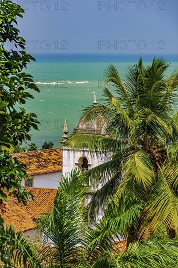 Baroque church tower hidden between vegetation and the sea in the historic city of Olinda in Pernambuco, Olinda, Pernambuco, Brazil, South America