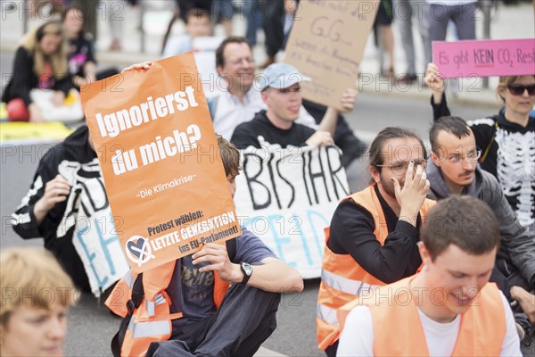 Last Generation activists with sign Ignore me? The climate crisis for the upcoming European elections at the occupation of Rahel-Deer-Straße in front of Berlin Central Station, Berlin, 25 May 2024