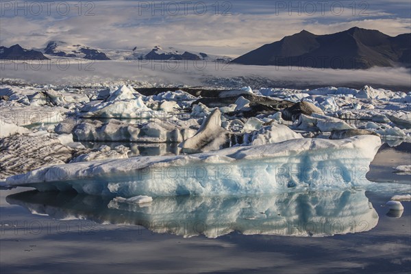 Ice floes, icebergs, reflection, mountains, clouds, sunny, Jökulsarlon, Vatnajökull, Iceland, Europe