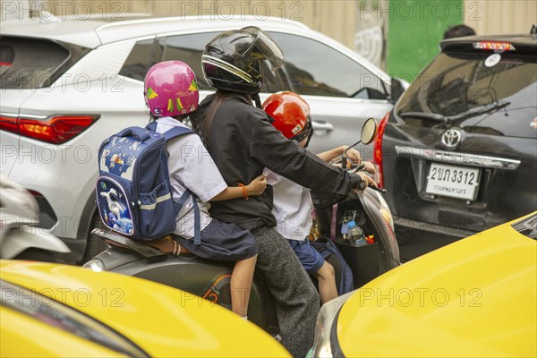 Mother with her two daughters in school uniform on a motorbike, rush hour, Bangkok, Thailand Asia