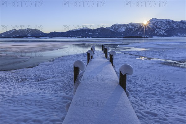 Sunrise at a lake in front of mountains, footbridge, snow, winter, Forggensee, Königswinkel, view of Tegelberg, Alpine foothills, Upper Bavaria, Bavaria, Germany, Europe