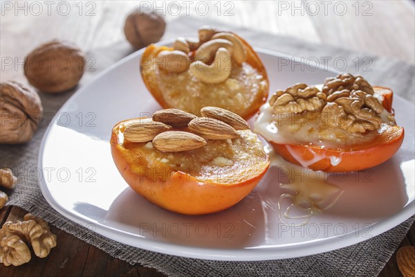 Persimmon dessert with curd, nuts and milk cream on brown wooden background. close up