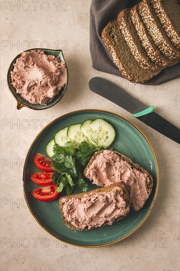 Liver meat pate spread on rye bread, breakfast, close-up, beige background. no people, selective focus