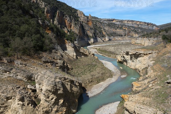 A clear river flows through a rocky gorge between overgrown mountains under a blue sky, Noguera Ribagorçana Mont-rebei Natural Park, Montsec mountain range, Noguera Ribagorçana river, Lleida province, Catalonia, Aragon, Spain, Europe