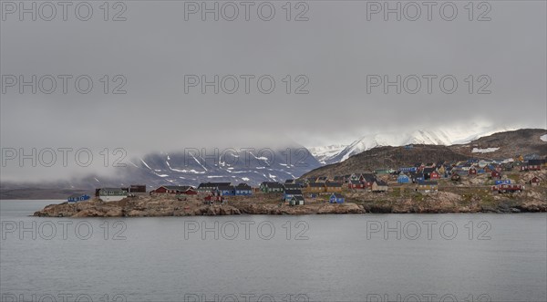 Colourful houses, secluded Arctic Inuit settlement, cloudy coastal landscape against a mountain backdrop, Ittoqqortoormiit, Scoresbysund or Scoresby Sund or Kangertittivaq in Greenlandic, East Greenland, Greenland, North America