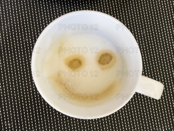 Coffee drink cappuccino with milk foam decorated to smile like emoji smiley, international