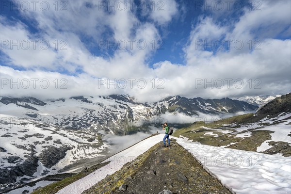 Mountaineer photographed on hiking trail, mountain landscape with snowfields, summit Hoher Weißzint and Hochsteller with glacier Schlegeiskees, Berliner Höhenweg, Zillertal Alps, Tyrol, Austria, Europe