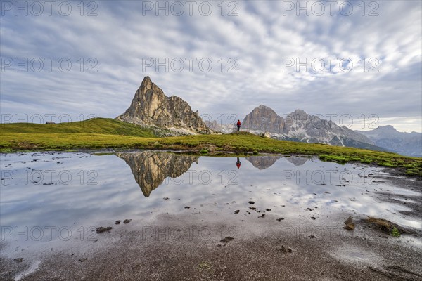 Reflection of the mountains at Passo di Giau, Monte Ragusela, woman with red rucksack, Dolomites, Cortina d'Ampezzo, Belluno, Veneto, Italy, Europe