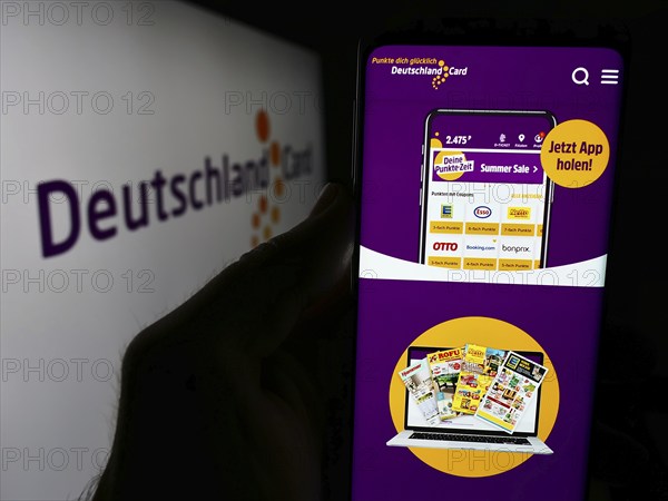 Stuttgart, Germany, 07-15-2024: Person holding smartphone with webpage of German customer loyalty company DeutschlandCard GmbH in front of logo. Focus on center of phone display, Europe