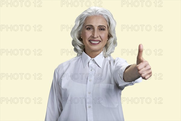 Beautiful smiling senior lady showing thumb up gesture. Isolated on white background