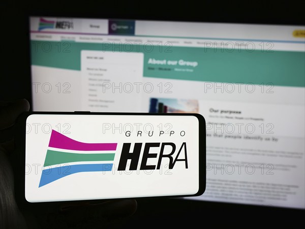 Stuttgart, Germany, 06-01-2024: Person holding smartphone with logo of Italian utility company Hera S.p.A. in front of website. Focus on phone display, Europe