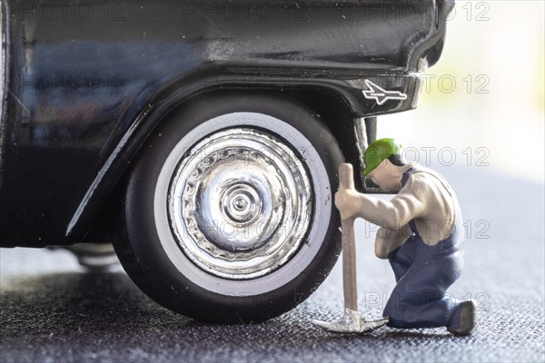 OLDENZAAL, NETHERLANDS, APRIL 2, 2022: Miniature construction worker kneeling next to an enormous car wheel