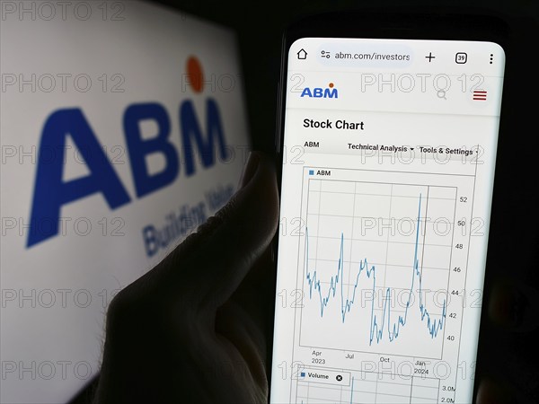 Stuttgart, Germany, 03-13-2024: Person holding cellphone with webpage of US facility management company ABM Industries Inc. in front of logo. Focus on center of phone display, Europe