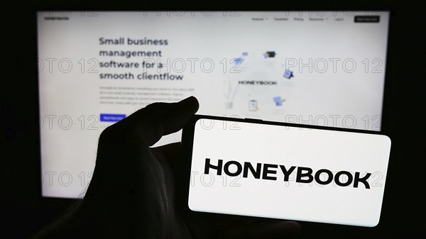 Stuttgart, Germany, 07-14-2024: Person holding smartphone with logo of US clientflow management company HoneyBook Inc. in front of website. Focus on phone display, Europe