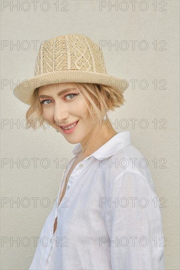 Lifestyle portrait of tricky young woman with healthy skin in white shirt and straw hat