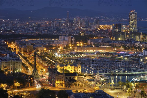 BARCELONA, SPAIN, APRIL 15, 2019: Aerial view of Barcelona city skyline with city traffic and port with yachts illuminated in the night. Barcelona, Spain, Europe